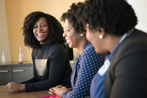 three women sitting beside wooden table